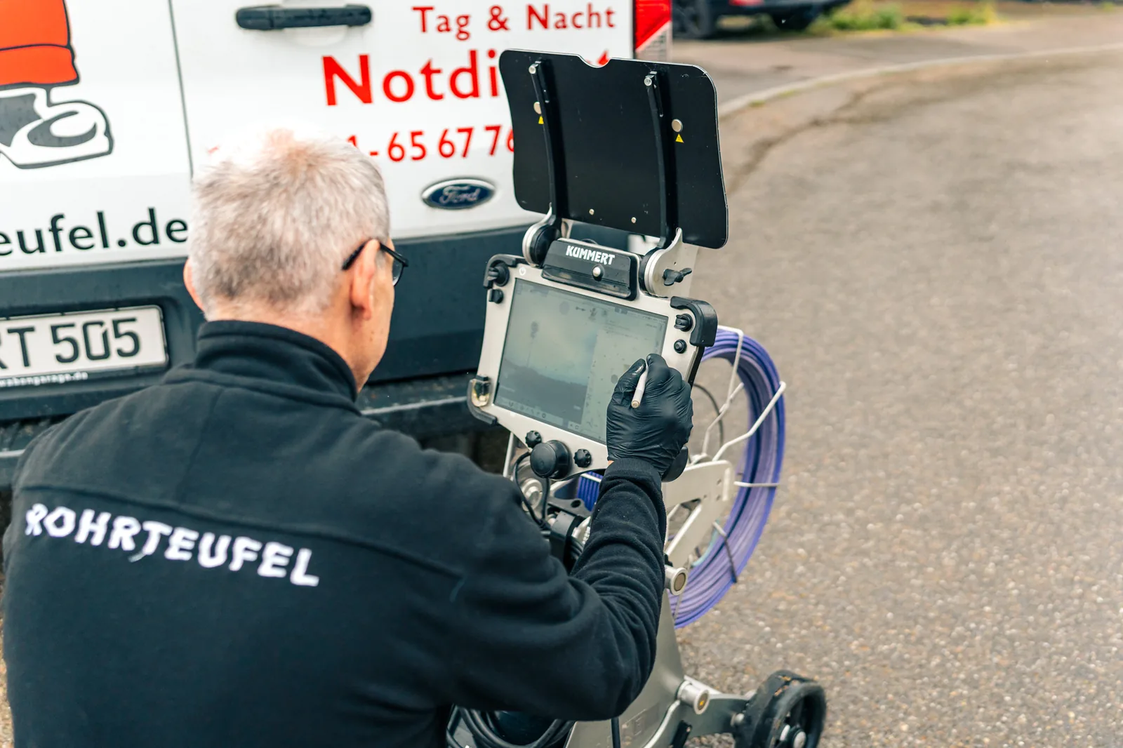 Techniker zeigt Hausbesitzer Live-Bilder aus der Kanalkamera