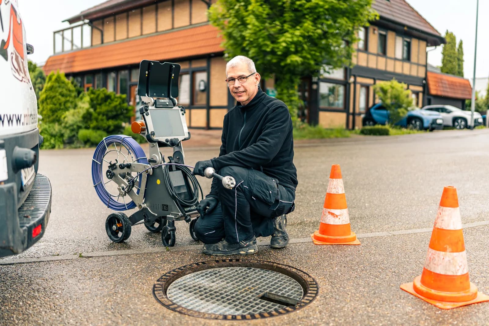 Techniker reinigt Kanal per Hochdruckspülung am Haus