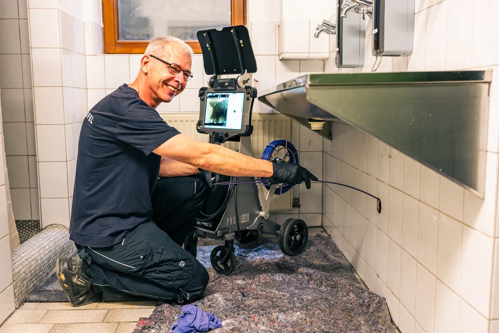 Techniker reinigt einen verstopften Küchenabfluss beim Kunden